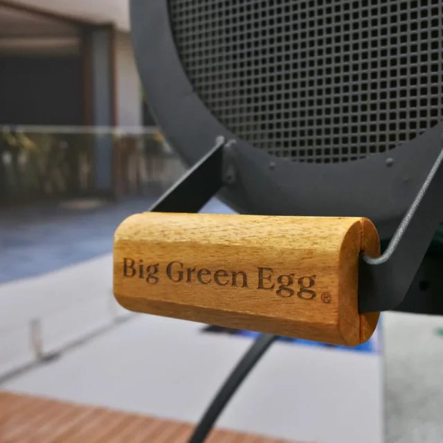 Akácfa fogantyú Big Green Egg felirattal, közelről fotózva a kandalló rácsánál