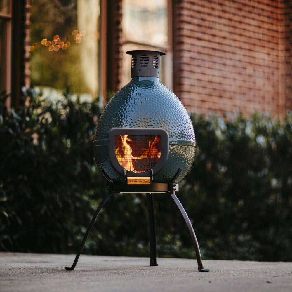 Big Green Egg Chiminea kültéri kandalló esti fényekben, díszburkolaton elhelyezve
