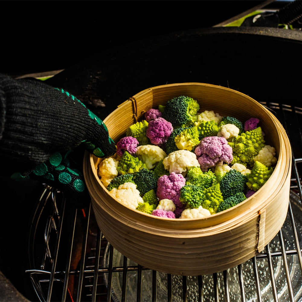 Színes zöldségek bambusz gőzölőkosárban Big Green Egg grillben, párolásra előkészítve csepegtető tálca felett

