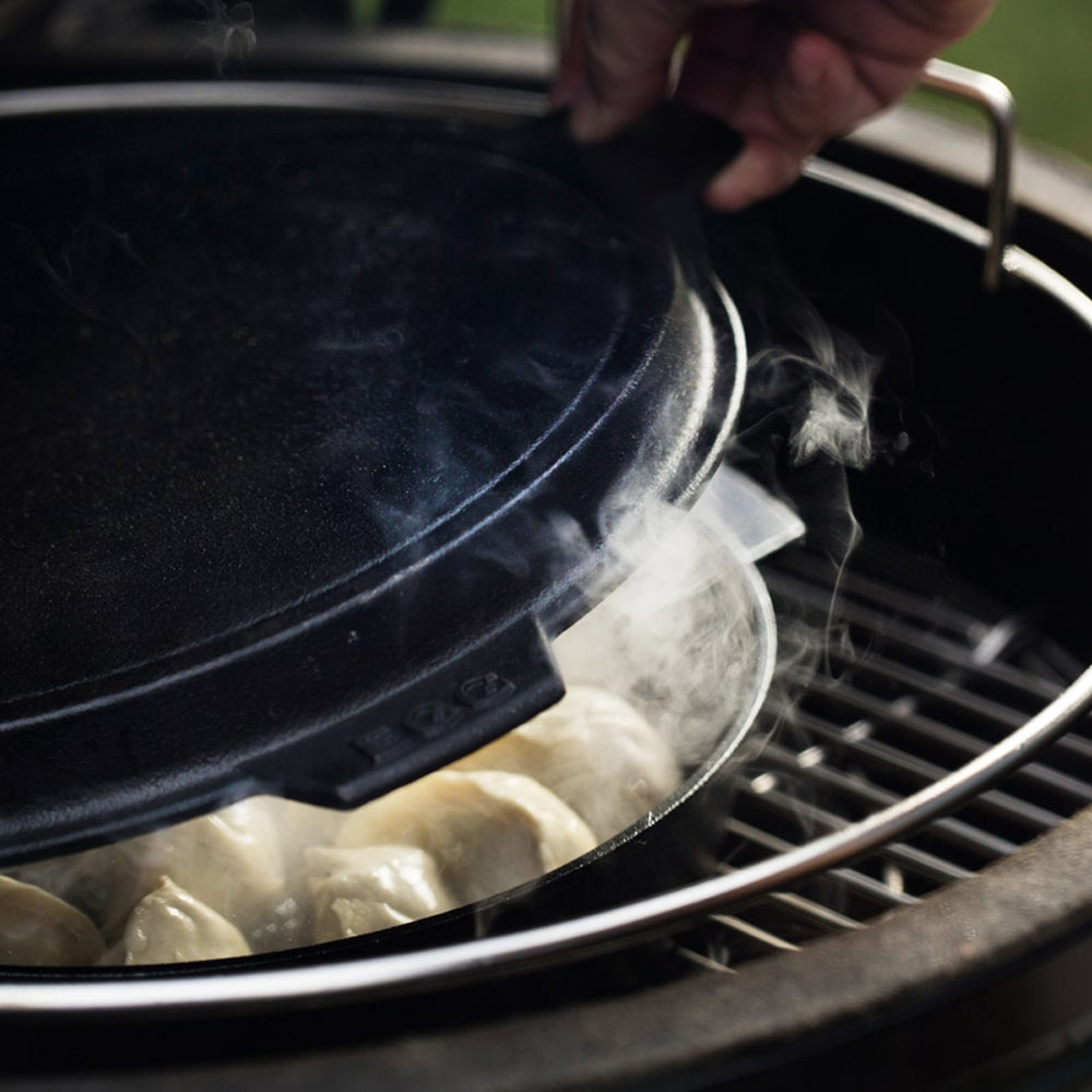 Big Green Egg grillben gőzölgő tésztabatyuk öntöttvas fedő alatt, gőzölési folyamat közben

