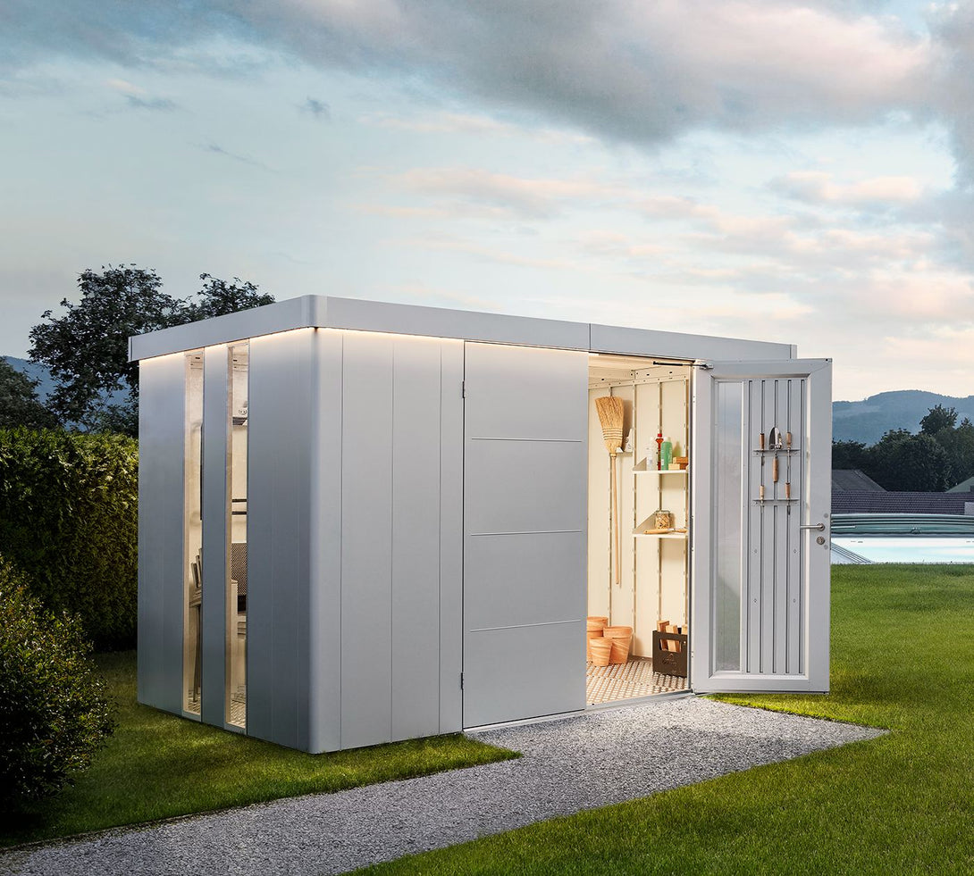 Modern Biohort Neo kerti tároló nyitott ajtóval, belső világítással, rendezett eszközökkel és háttérben medencés kerttel.