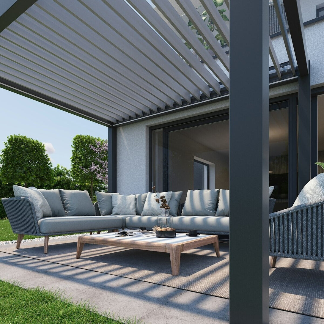 Biohort pergola sötétszürke-metál színű vázzal, modern terasz fölé építve, alatta elegáns kültéri ülőgarnitúrával és fa dohányzóasztallal.