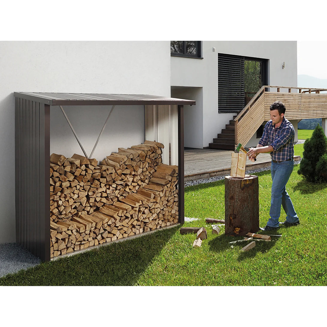Biohort Woodstock tűzifatároló modern ház falánál, benne rendezett farakással, előtérben favágó férfival.