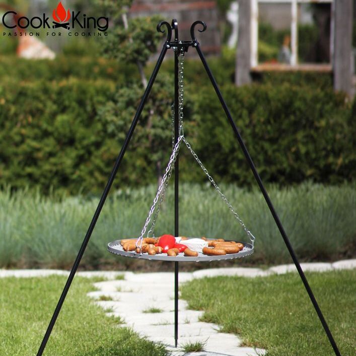 Cook King 180 cm-es háromlábú grill rozsdamentes acél grillráccsal (50–80 cm), használatban.