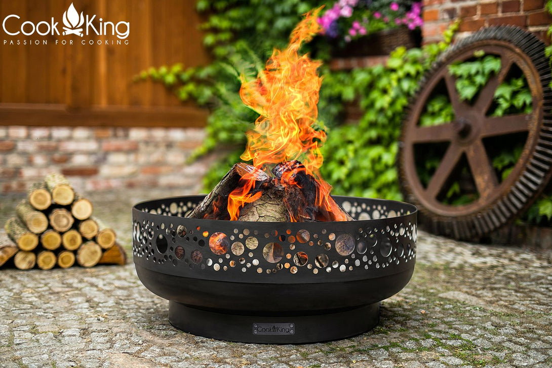 Cook King BOSTON kerti tűztál – lézervágott peremű, kézzel készült nyersacél tűzrakó (80 cm) - használatban, lobogó tűzzel.