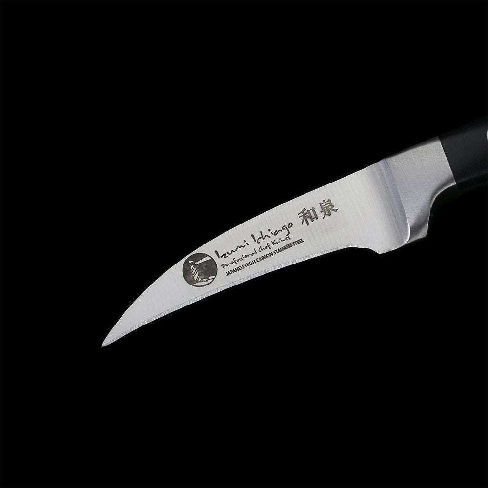 Rövid, ívelt rozsdamentes acél penge a tourné késen, logó és felirat közelről.