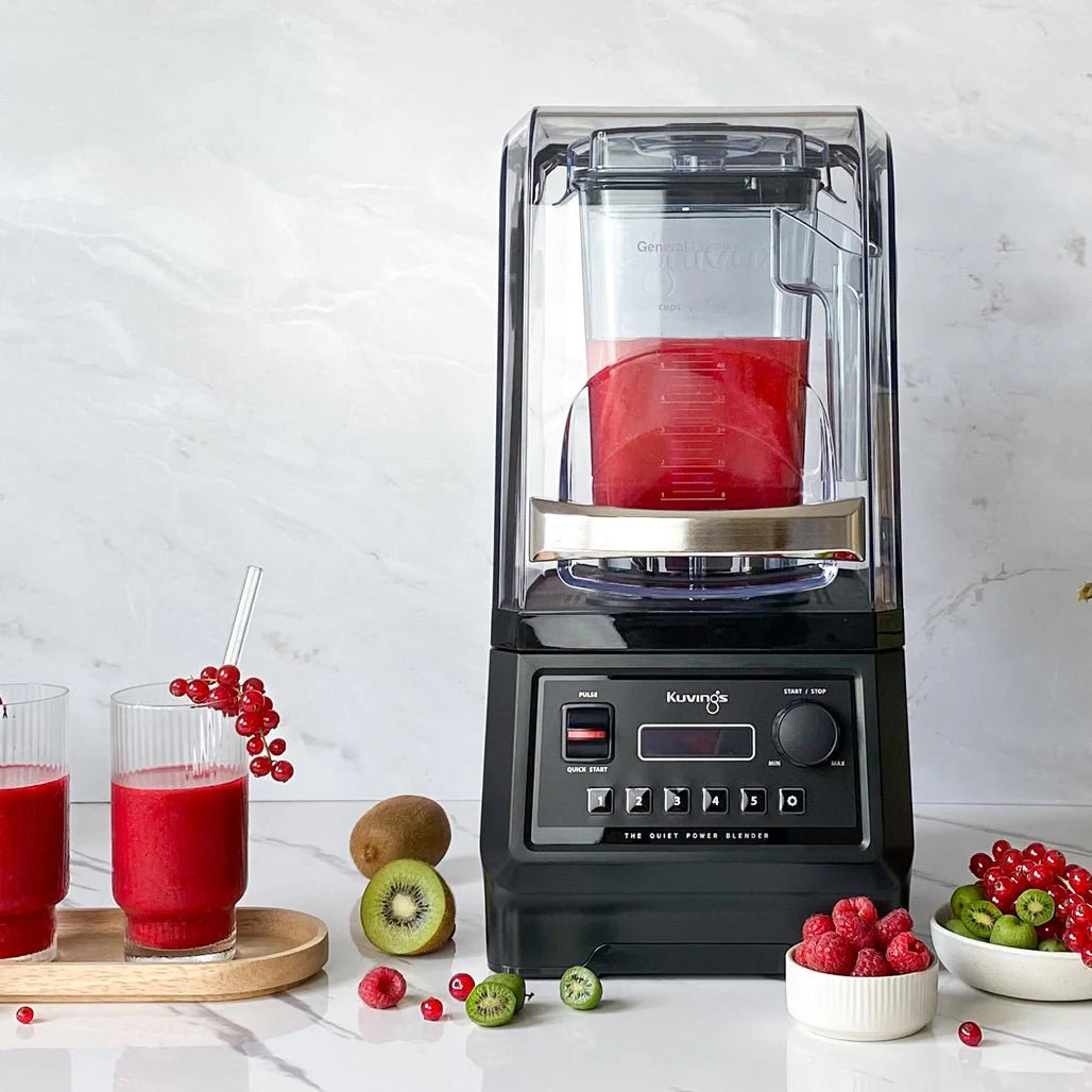 Kuvings CB850 professzionalis turmixgep zajvedo burkolattal, piros smoothie-val es poharakkal a pulton