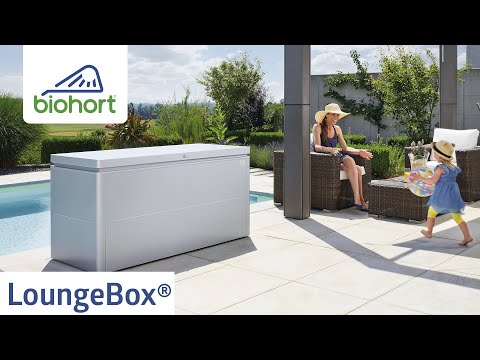Biohort LoungeBox® ezüstmetál kültéri tároló elegáns teraszon, pihenő nővel és játszó kislánnyal; háttérben gondozott kert és medence, a képen a Biohort logó is látható.